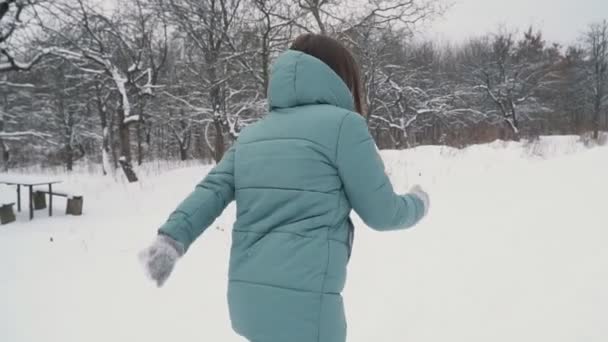 Девушка бежит через снежный парк — стоковое видео