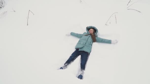 Menina fazendo anjo na neve — Vídeo de Stock