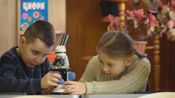 Дівчина дивиться через мікроскоп — стокове відео