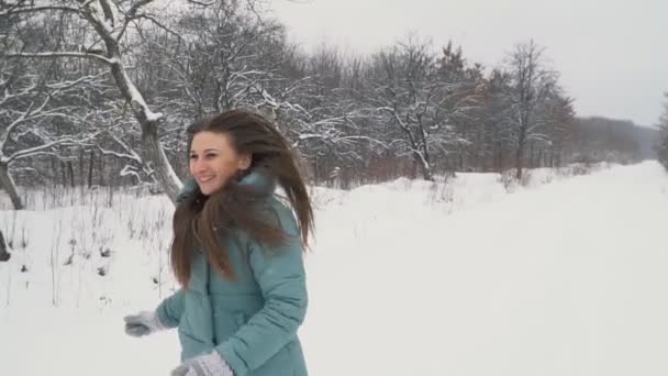 Flickan rinner genom den snöiga parken — Stockvideo