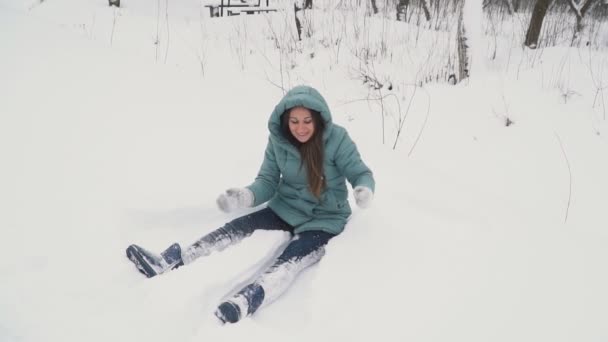 Девушка делает ангела в снегу — стоковое видео