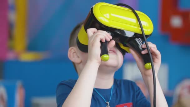 Маленький мальчик в шлеме виртуальной реальности играет в игры — стоковое видео