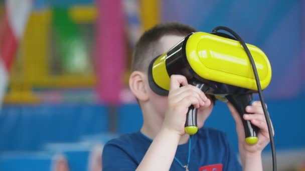 Pequeño niño en un casco de realidad virtual juega juegos — Vídeos de Stock