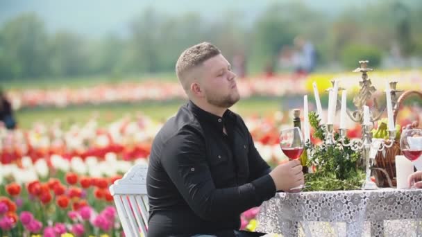 Человек пьет вино сидя за столом — стоковое видео