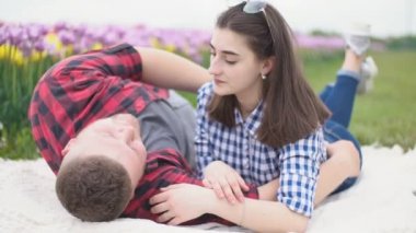 Genç bir çift battaniyeye uzanıp konuşuyor.