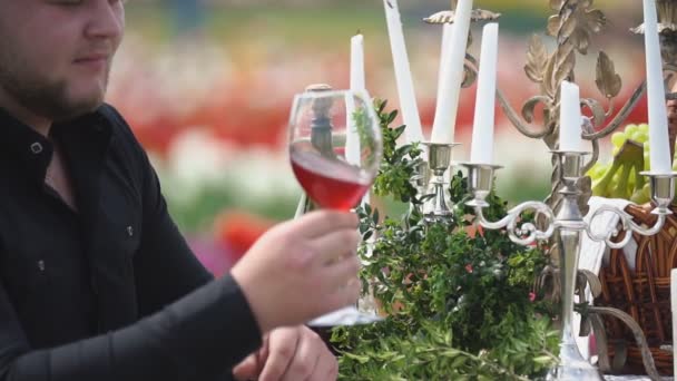 Человек пьет вино сидя за столом — стоковое видео