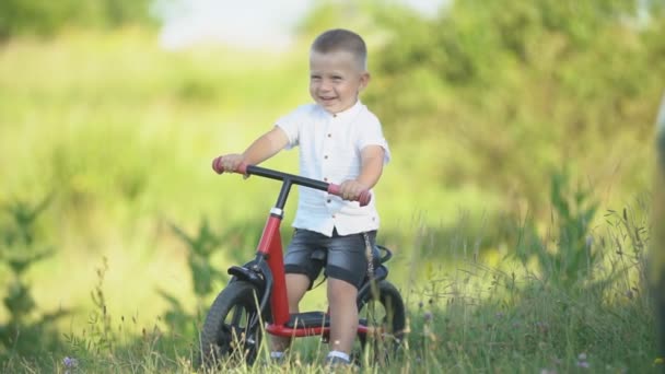 Een jongen rijdt een fiets zonder pedalen — Stockvideo