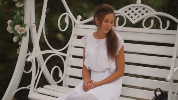 Жінка в білій сукні гойдається на гойдалці — стокове відео