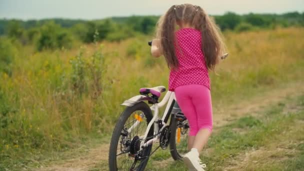 Маленькая девочка с велосипедом в природе — стоковое видео