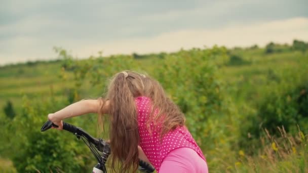 Liten flicka med en cykel i naturen — Stockvideo