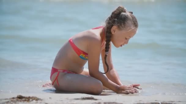 Meisje spelen met zand op het strand — Stockvideo