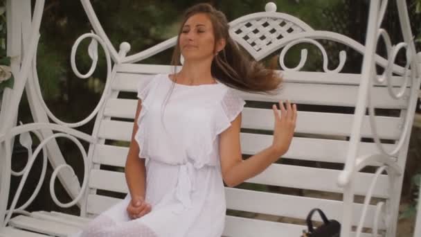 Женщина в белом платье качается на качелях — стоковое видео