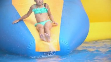 Kız su parkında yokuş aşağı gidiyor.