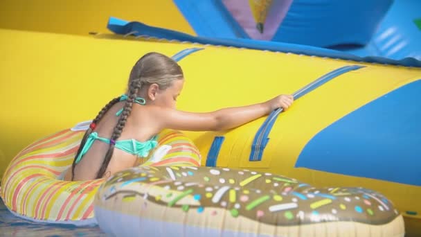 Menina sobe um slide em um parque aquático — Vídeo de Stock