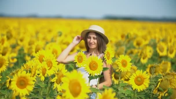 Ragazza in un cappello su uno sfondo di fiori di girasole — Video Stock