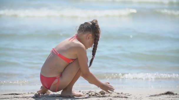Meisje spelen met zand op het strand — Stockvideo