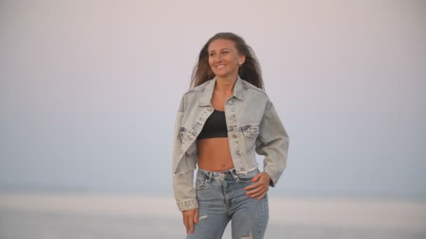 Mädchen in Jeans Kleidung auf einem Hintergrund des Meeres — Stockvideo