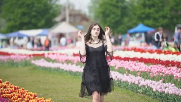 Flickan går nära tulpaner — Stockvideo