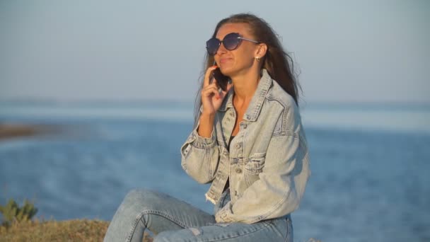 Девушка в солнечных очках разговаривает по телефону — стоковое видео