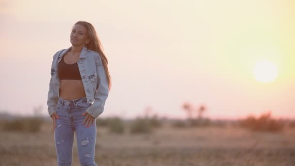 Chica en jeans contra la puesta del sol cielo — Vídeo de stock