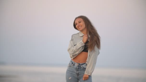 Flicka i jeans kläder på en bakgrund av havet — Stockvideo