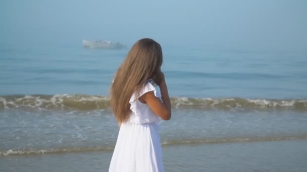 Mädchen in weißem Kleid geht am Meer entlang — Stockvideo