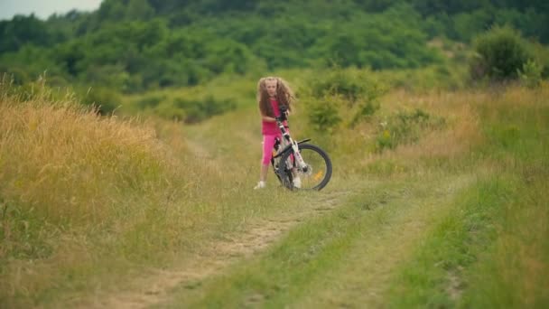 Menina com uma bicicleta andando em uma estrada de terra — Vídeo de Stock