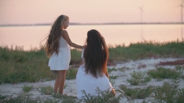 Mamma och dotter sitter på stranden och tittar in i fjärran — Stockvideo