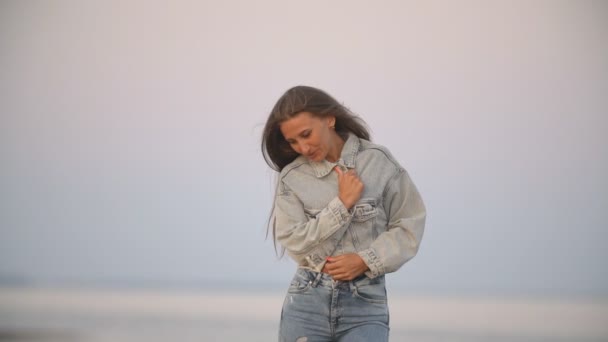 Mädchen in Jeans Kleidung auf einem Hintergrund des Meeres — Stockvideo
