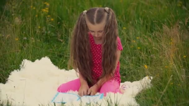Dívka čte knihu, která sedí na trávníku — Stock video