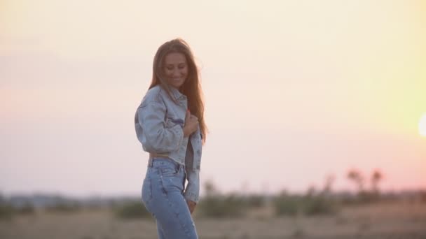 Девушка в джинсах одежда против заходящего солнца — стоковое видео