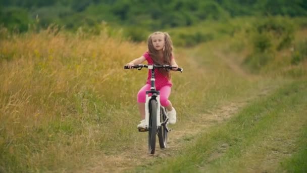 Fille monte un vélo sur la route envahi par l'herbe — Video