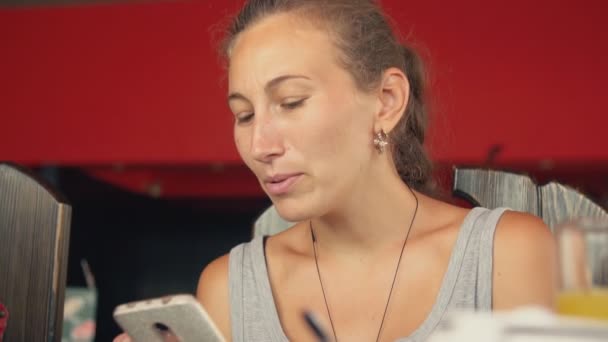 Vrouw praat met iemand tijdens het kijken naar de telefoon — Stockvideo