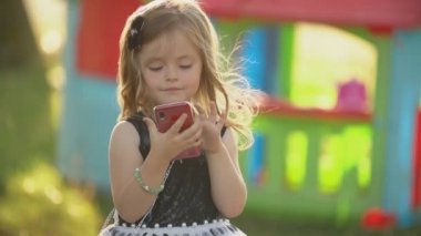 çocuk elinde bir telefon ile oturur