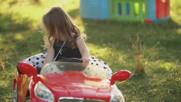 Niño monta un coche rojo — Vídeos de Stock