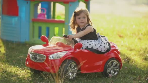 Niño monta un coche rojo — Vídeos de Stock