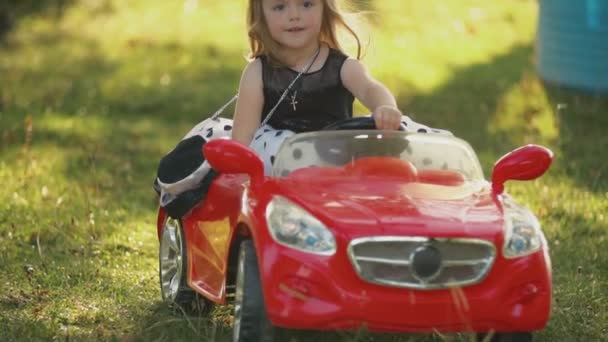 Παιδί βόλτες με ένα κόκκινο αυτοκίνητο — Αρχείο Βίντεο