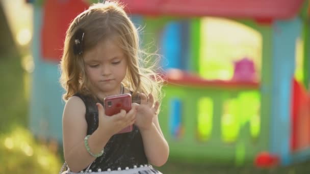 Gyermek ül egy telefonnal a kezében — Stock videók