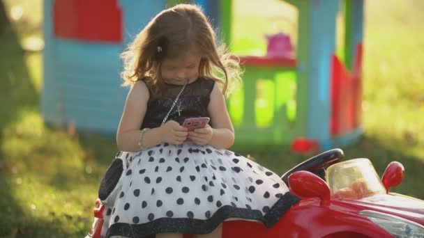 Ребенок сидит с телефоном в руках — стоковое видео
