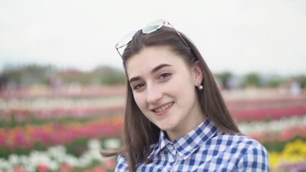 Retrato de uma menina no fundo de flores coloridas — Vídeo de Stock