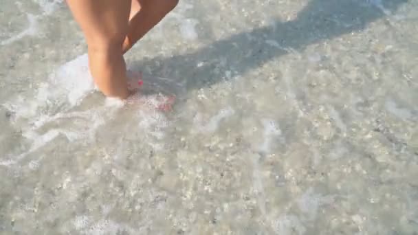 Kvinnliga ben promenad på ett grunt hav — Stockvideo