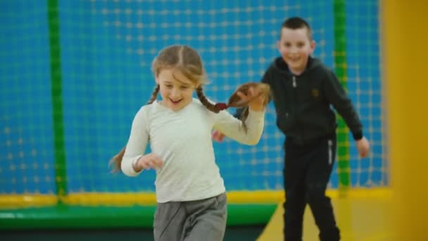 Kinderen spelen catch-up op trampolines — Stockvideo