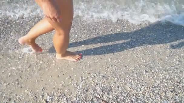 Piernas femeninas caminan sobre un mar poco profundo — Vídeo de stock