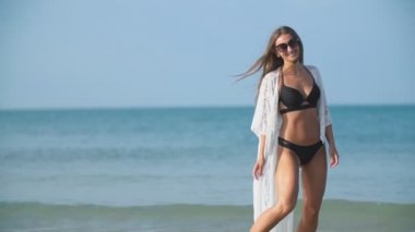 Kız deniz kenarında yürüyor.