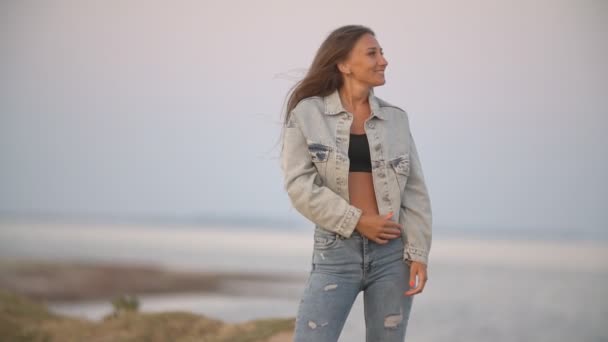 Meisje in jeans kleren op een achtergrond van de zee — Stockvideo