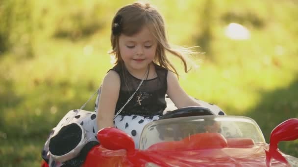Маленькая девочка едет на красной машине — стоковое видео