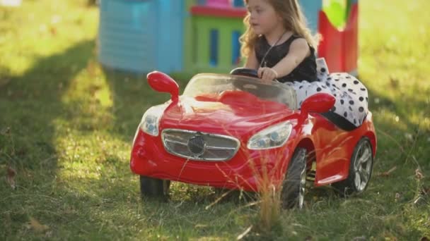 Kleines Mädchen auf einem roten Auto — Stockvideo