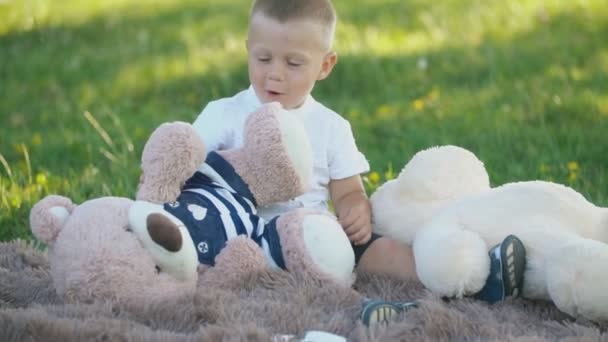 Chłopiec z miękkimi zabawkami siedzi na kocu — Wideo stockowe