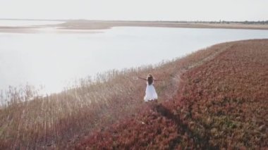 beyaz elbiseli kız deniz kıyısında yürür