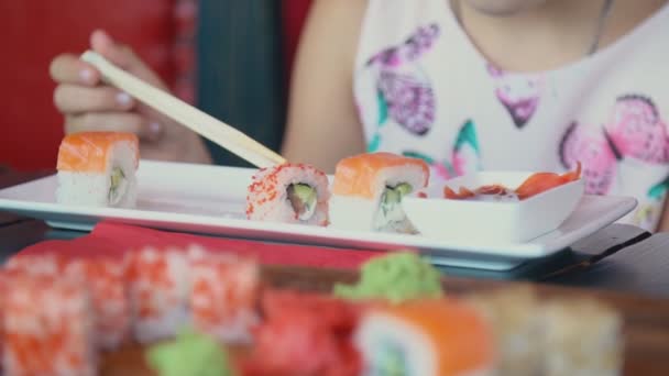 Niña comiendo sushi con palillos — Vídeo de stock